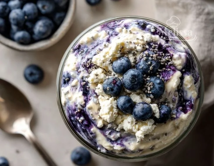 Bowl of blueberry cottage cheese overnight oats topped with fresh blueberries