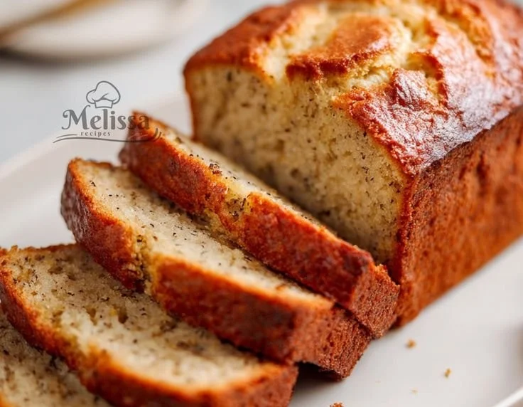 High protein banana bread slice on a plate with banana and nuts