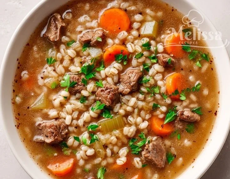 Slow cooker beef barley soup in a bowl with fresh herbs.