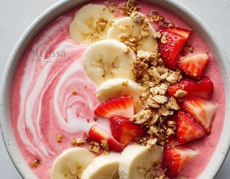 Strawberry banana smoothie bowl topped with fresh fruit and granola