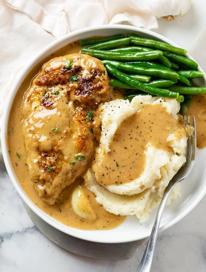 Plate of creamy garlic chicken with herbs and a side of vegetables