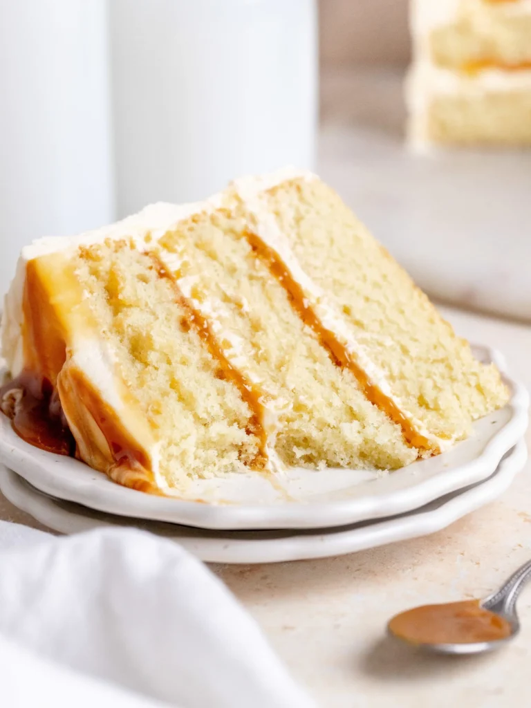 Slice of delicious salted caramel cake topped with caramel drizzle and sea salt