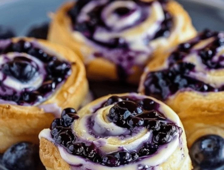 Easy blueberry cheesecake rolls with icing drizzle on a plate
