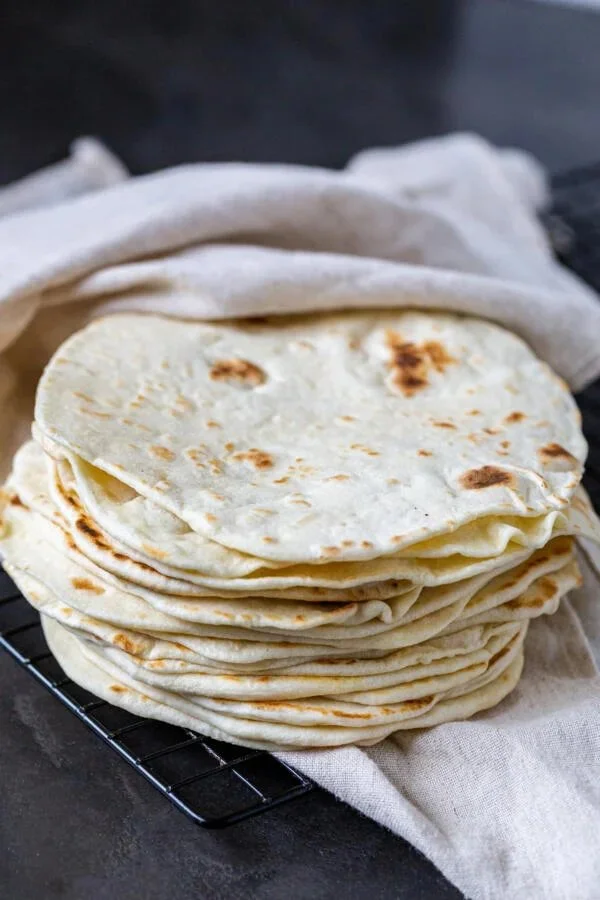 A stack of easy homemade tortillas on a wooden table.