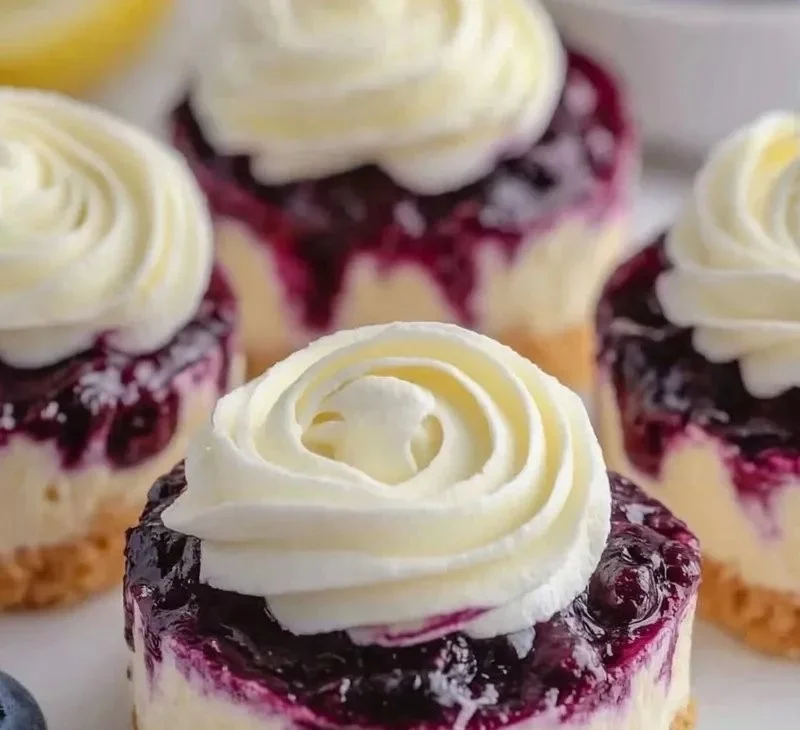 Mini lemon blueberry cheesecakes topped with fresh blueberries and lemon zest