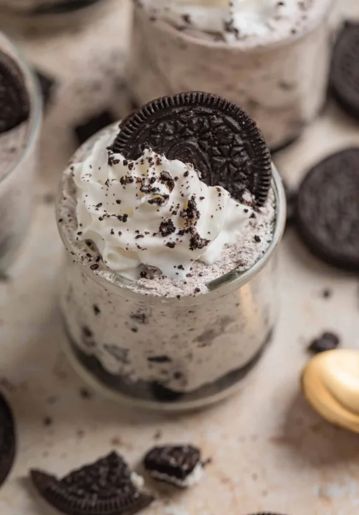 Oreo no-bake cheesecake cups topped with crushed Oreos and chocolate drizzle.
