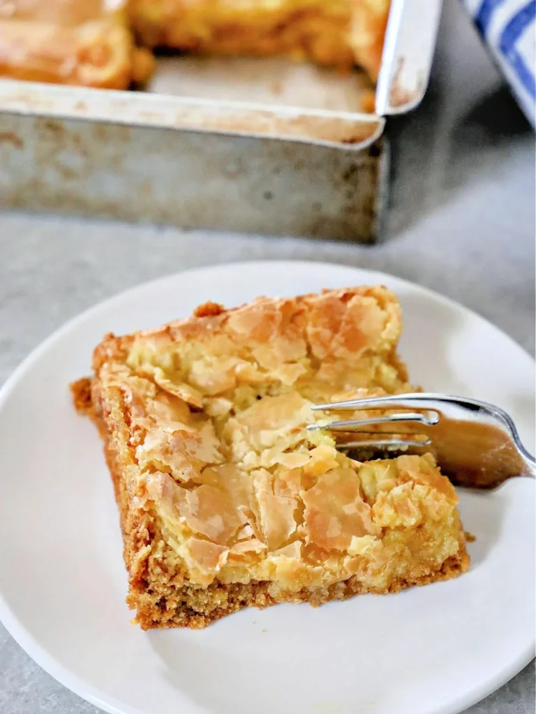 Paula Deen's oey gooey butter cake slice on a rustic table.