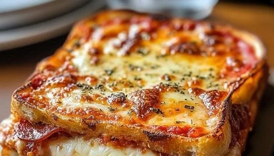 Melted cheese and savory pizza toppings in a grilled cheese sandwich