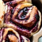 Soft cinnamon rolls topped with blueberries, fresh from the oven.