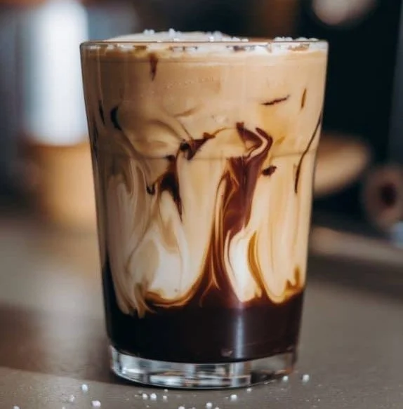 Delicious salted maple cold brew served in a glass with ice and maple syrup drizzle