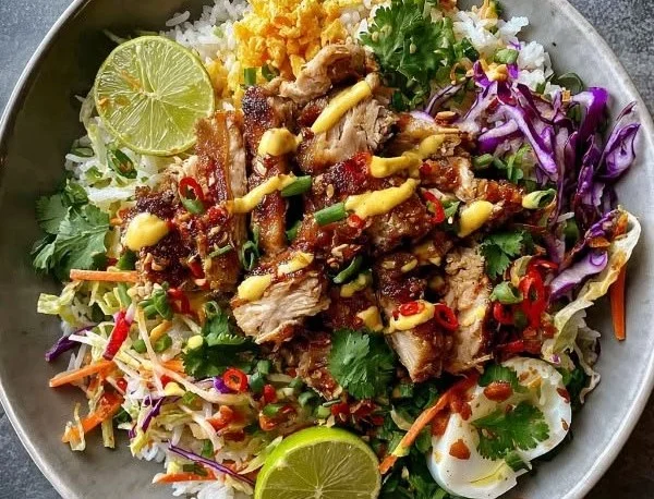 Crispy rice salad topped with Bang Bang Chicken, colorful veggies, and sauces