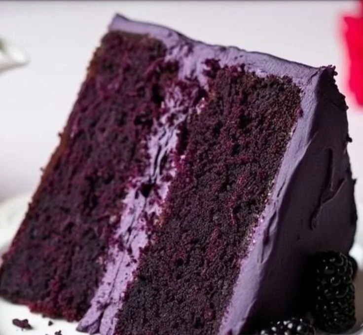Delicious slice of blackberry velvet cake on a white plate with fresh blackberries