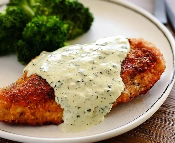 Plate of chicken in basil cream sauce garnished with fresh basil leaves