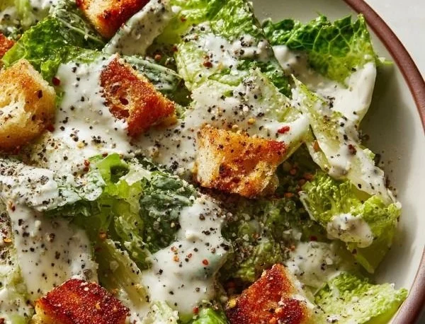 Creamy Greek Yogurt Caesar Dressing served in a bowl with salad ingredients