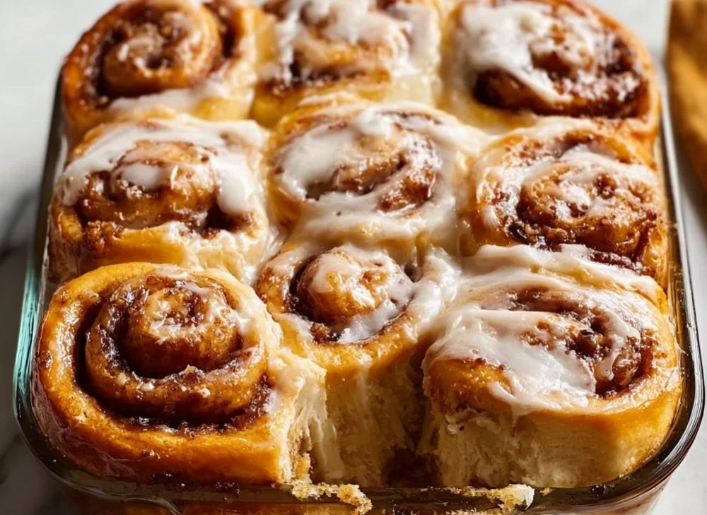 Fluffy banana bread cinnamon rolls with cream cheese frosting on a plate.