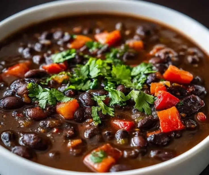 Bowl of hearty black bean soup garnished with cilantro and lime