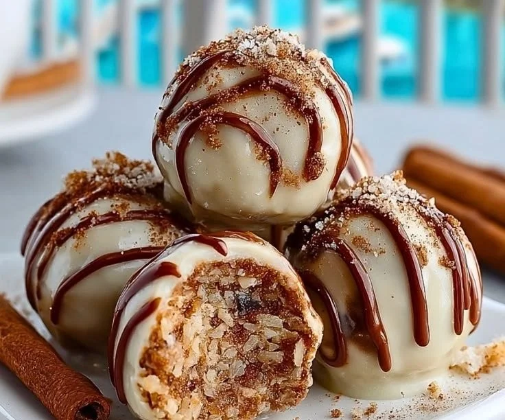 Image of no-bake cinnamon roll truffles topped with icing and sprinkled cinnamon.