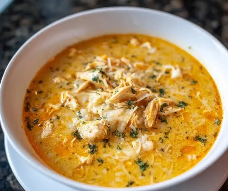 Bowl of creamy Parmesan Chicken Soup garnished with herbs and cheese