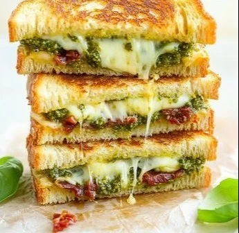 Pesto grilled cheese sandwich with melted cheese and fresh basil pesto