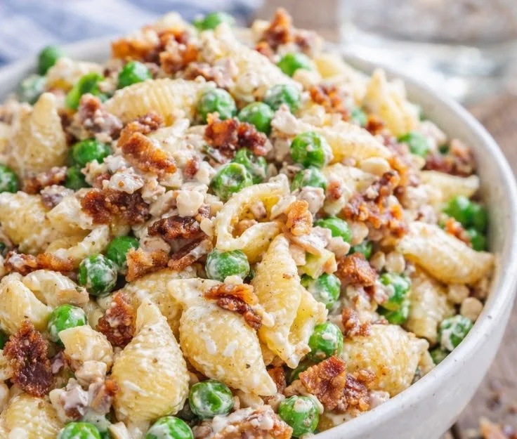 Creamy pasta salad with peas and bacon in a serving bowl