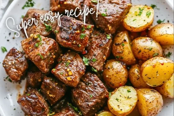 Plate of garlic steak bites with crispy potatoes served on a rustic table.