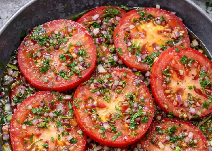 Delicious marinated tomato salad with fresh herbs and dressing.