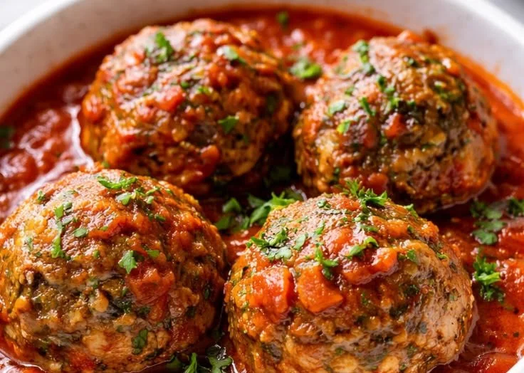 A plate of tender Italian-style beef meatballs with marinara sauce and parsley garnish