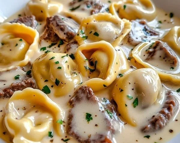 Cheesesteak Tortellini with creamy provolone sauce garnished with herbs