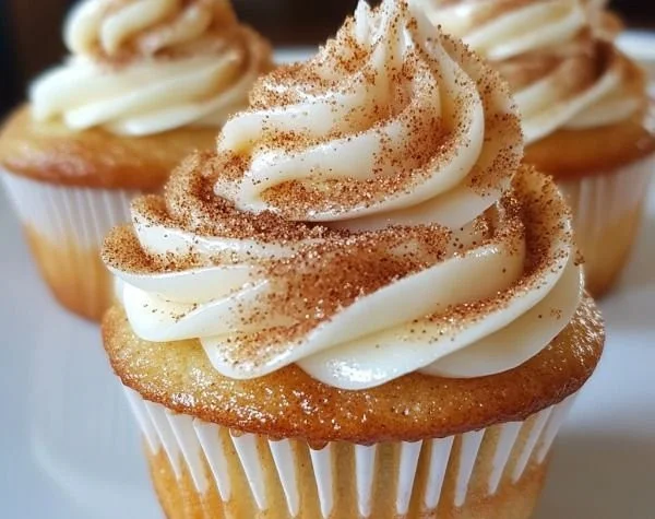 Delicious cinnamon roll cupcake topped with icing and cinnamon sugar.