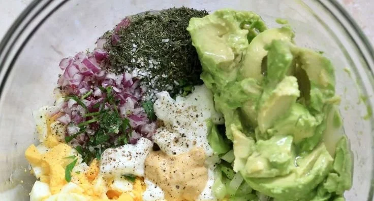 Herby avocado egg salad served in a bowl with fresh herbs