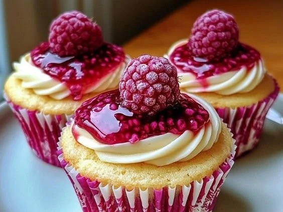 Raspberry cheesecake cupcakes topped with fresh raspberries and cream
