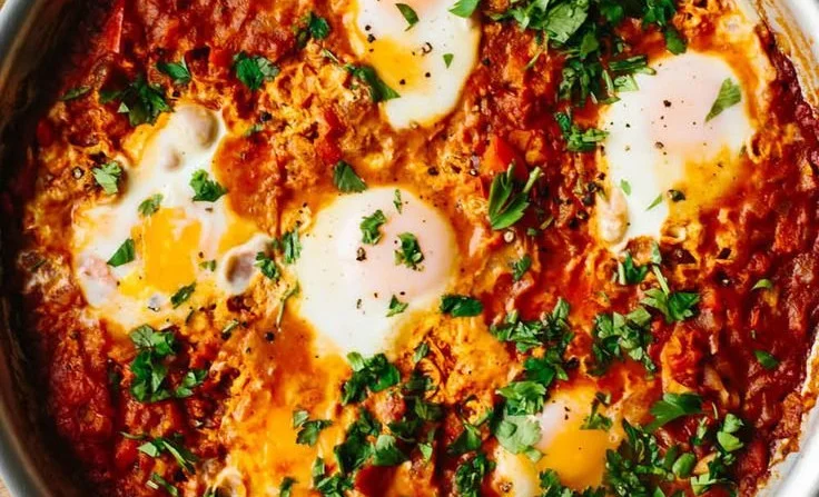 A vibrant plate of Shakshuka featuring poached eggs and rich tomato sauce.